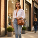 Woman holding a brown leather bag on a city street